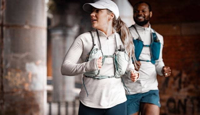 Two runners jogging under a bridge